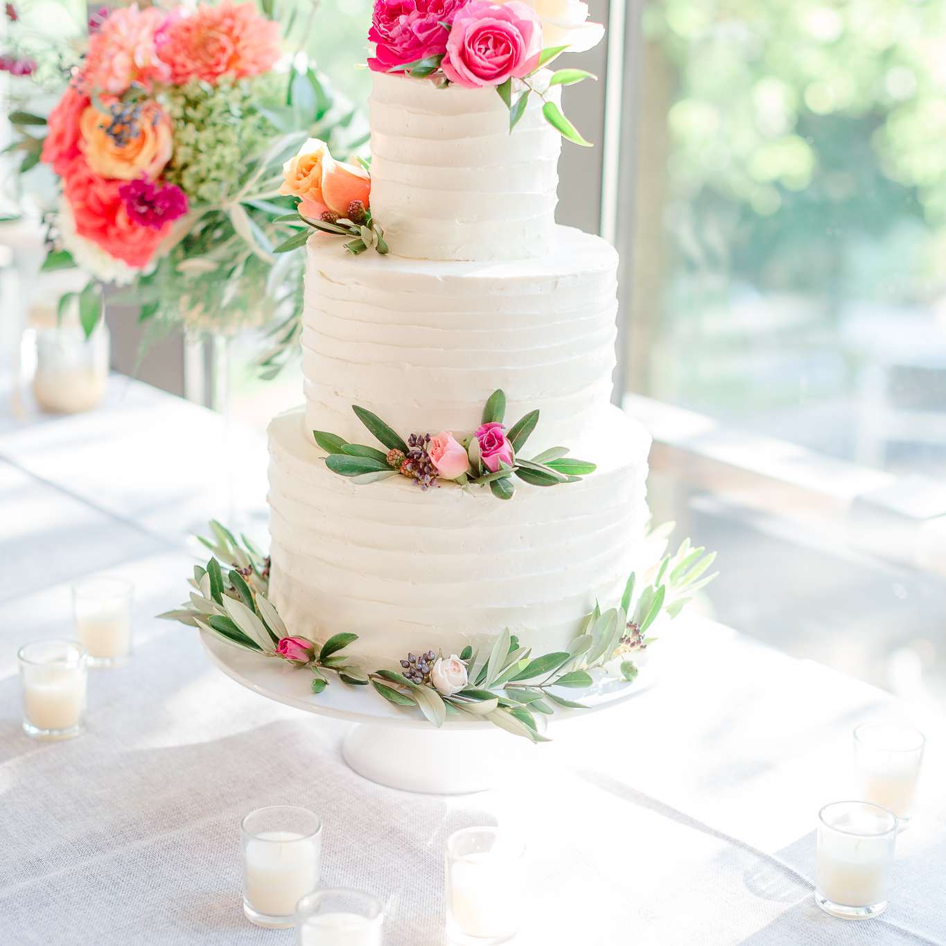 三层的白色婚礼蛋糕和粉红色的玫瑰