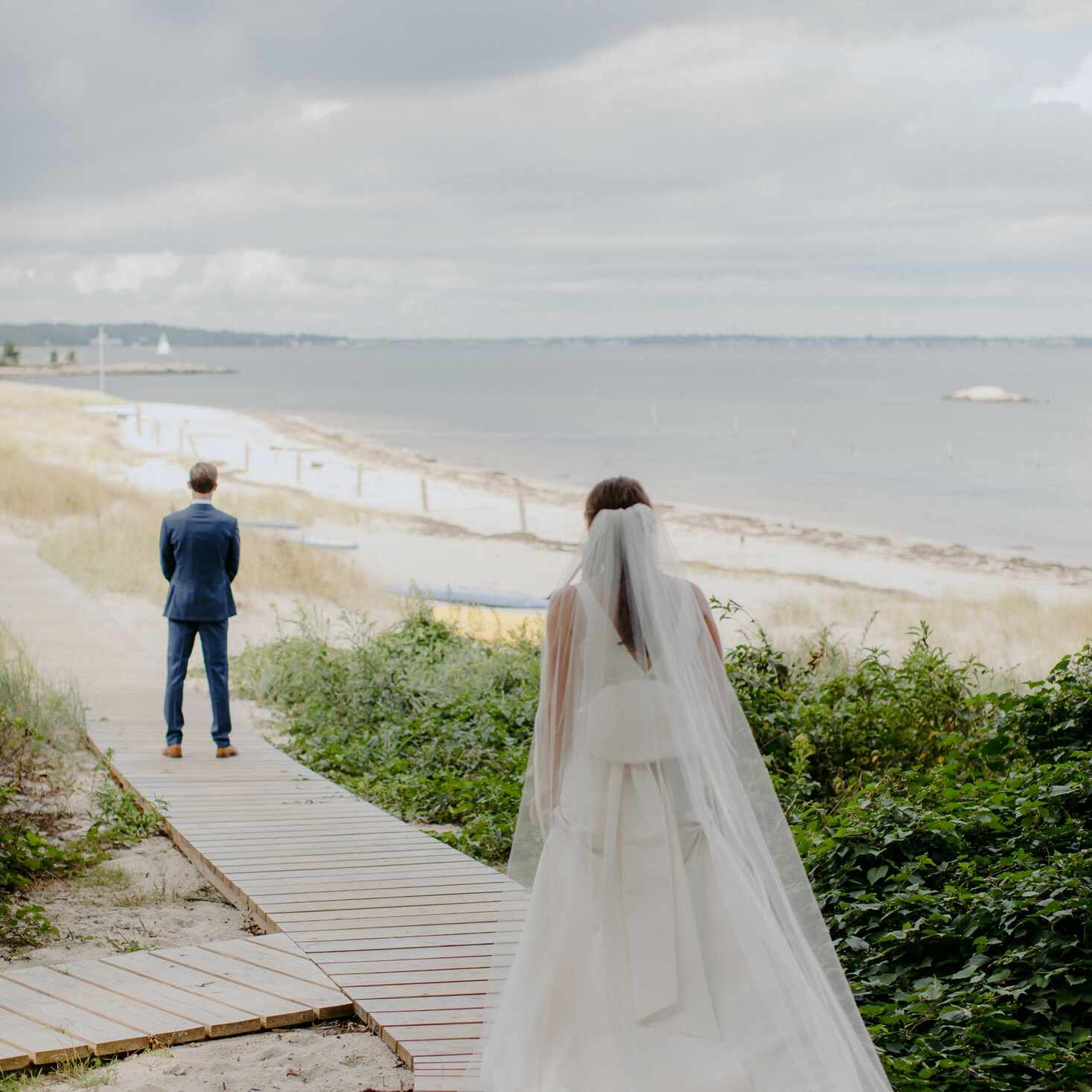 站立在海滩后的新娘在新郎后