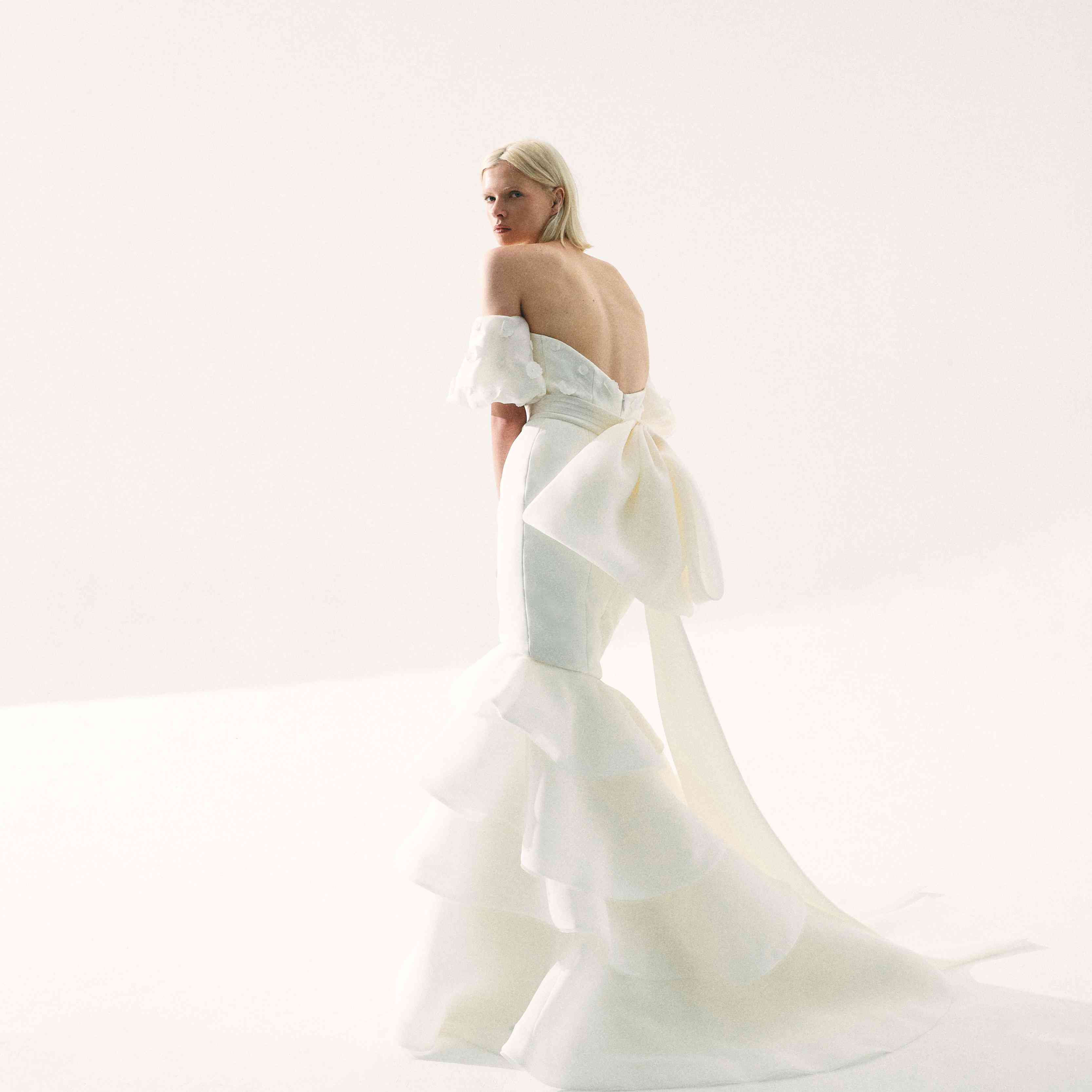 模型在肩膀上的美人鱼礼服，背面有裙子和大弓细节