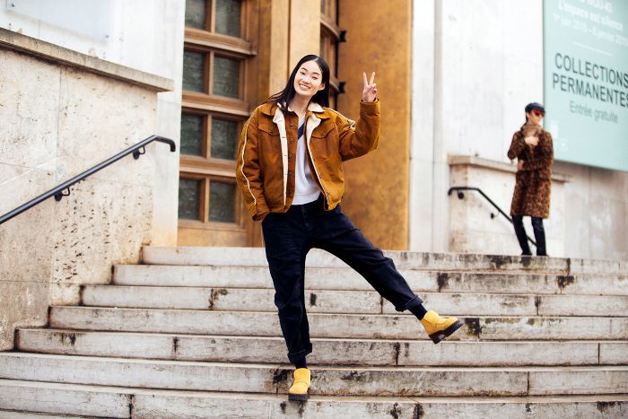 给和平标志的妇女，当站立在步时“class=