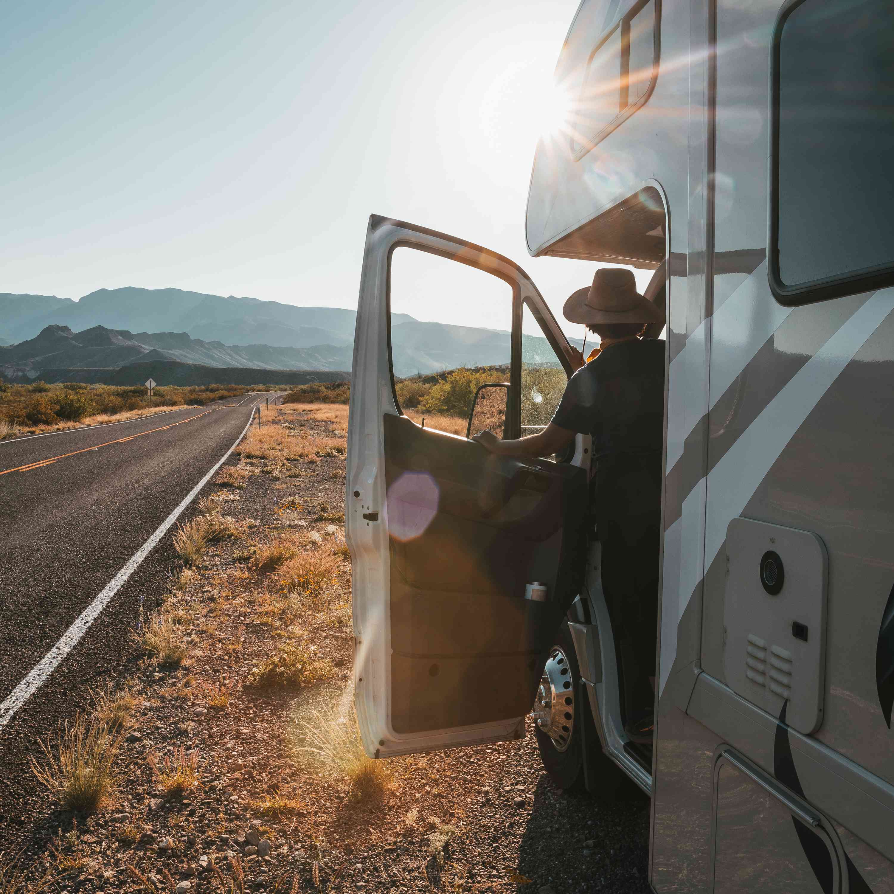 有来自Rvshare的RV的妇女在俯视山的风景公路旅行