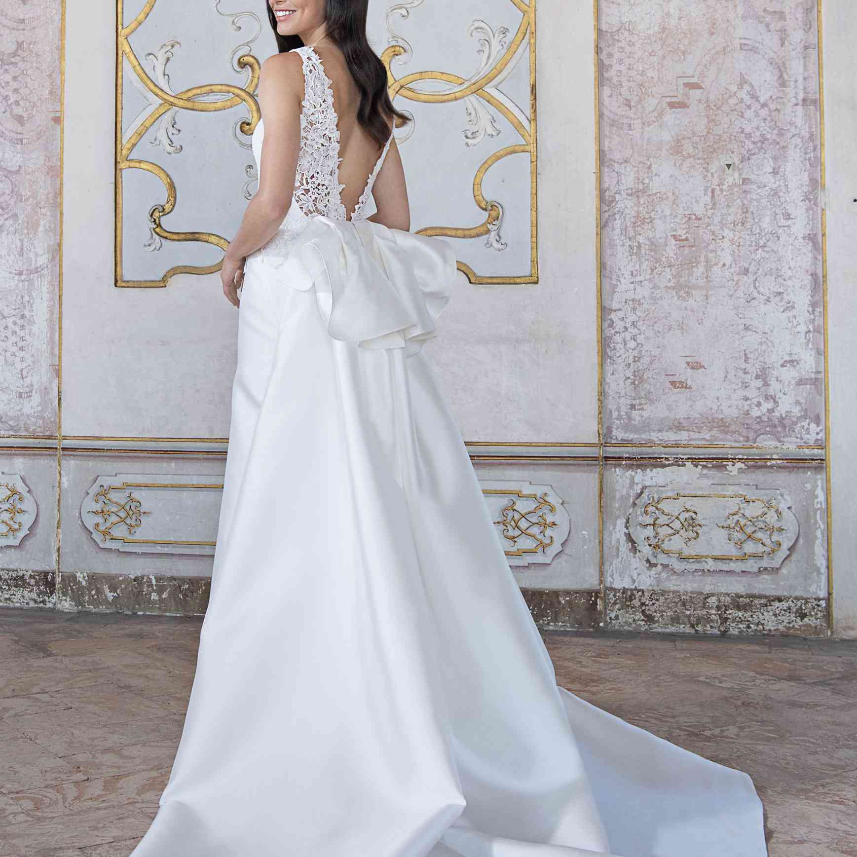 模特身着带有蕾丝紧身胸衣、v字背和超大蝴蝶结的长礼服