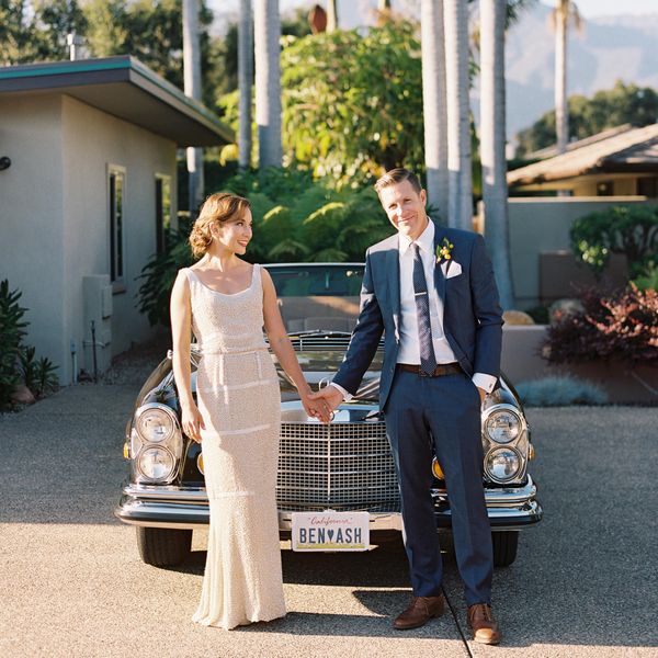 Bride and groom standing in front of car