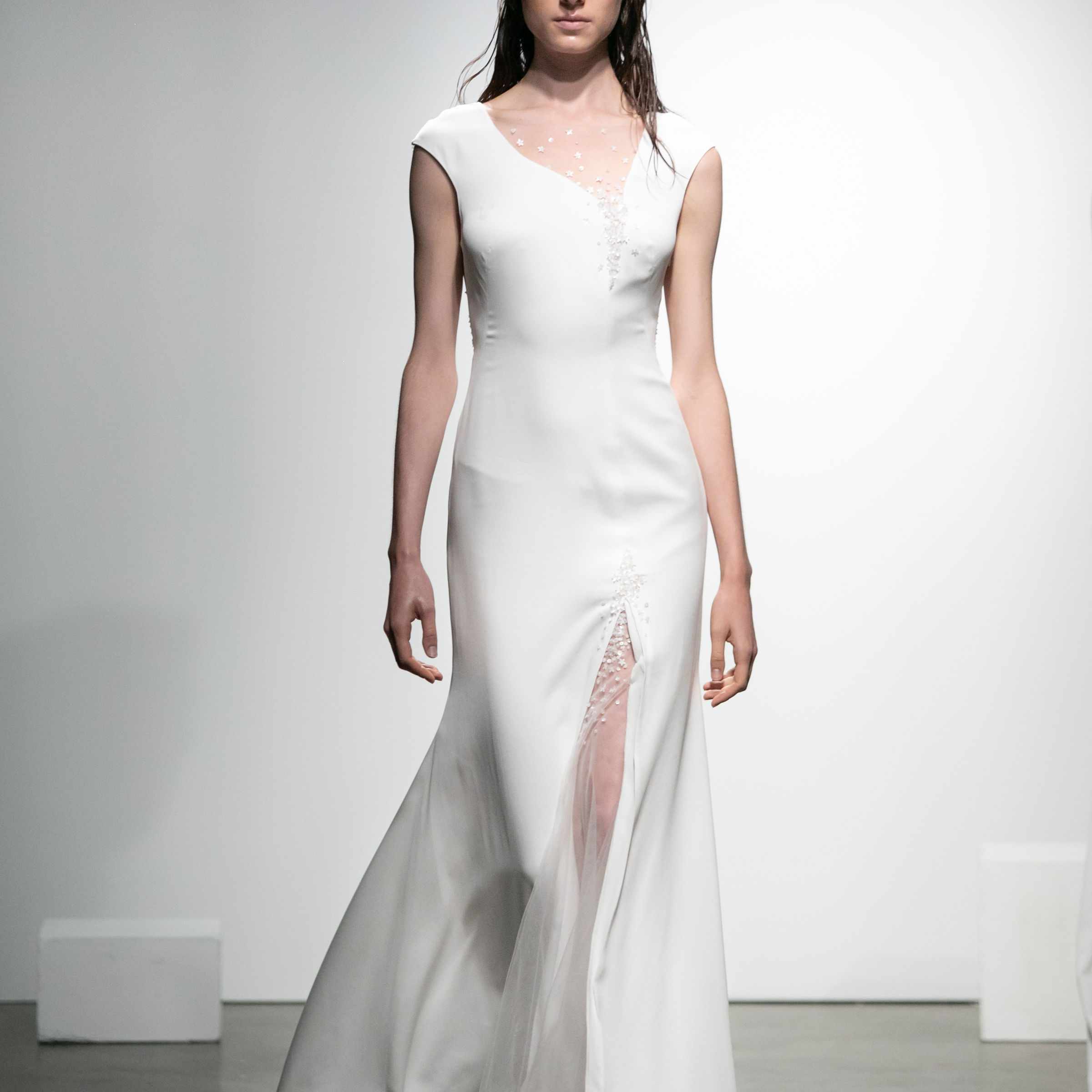 模特在绉连衣裙与花卉刺绣和珍珠裙狭缝