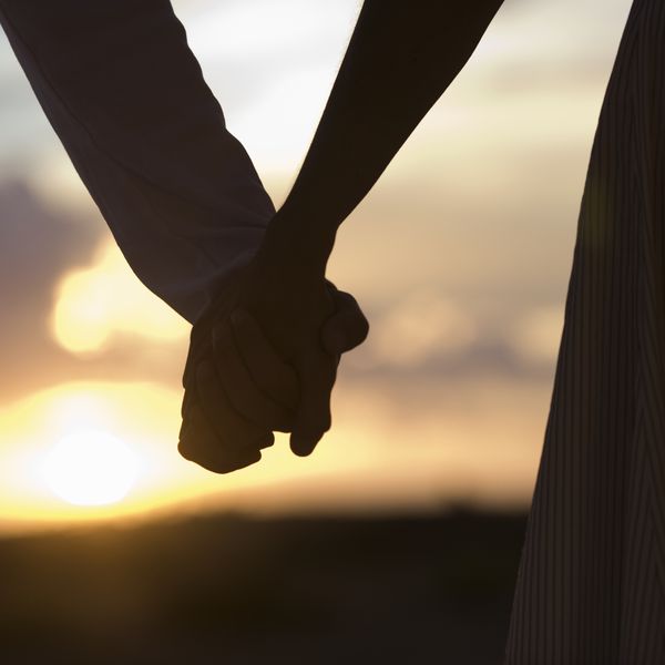 一对成熟的夫妇在日落时牵着手，特写