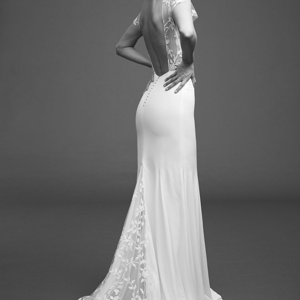 模特在绉连衣裙与刺绣薄纱，帽子袖子，和开放的背部