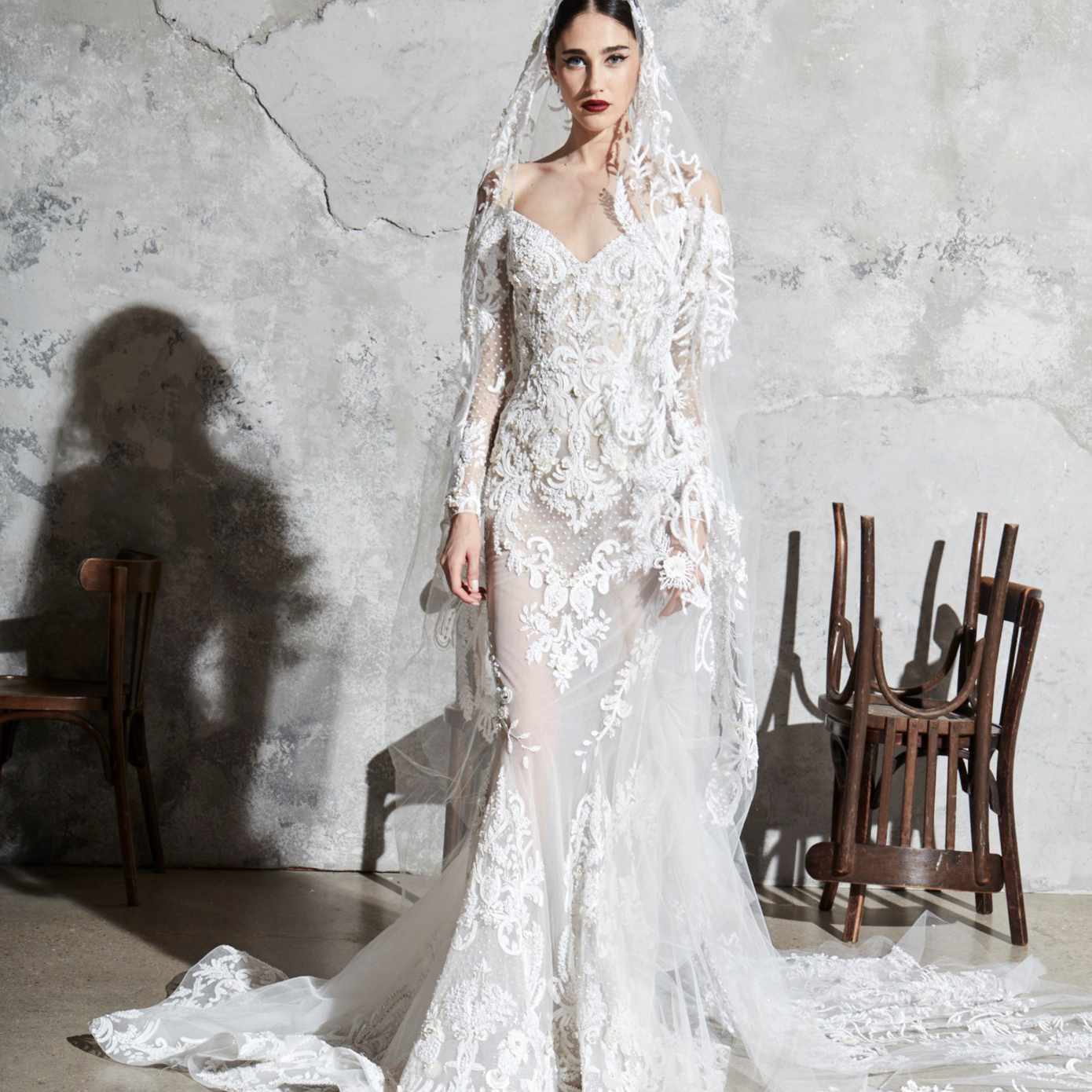 模特在露肩绣长袖丝质透明硬纱美人鱼礼服贴花和匹配面纱