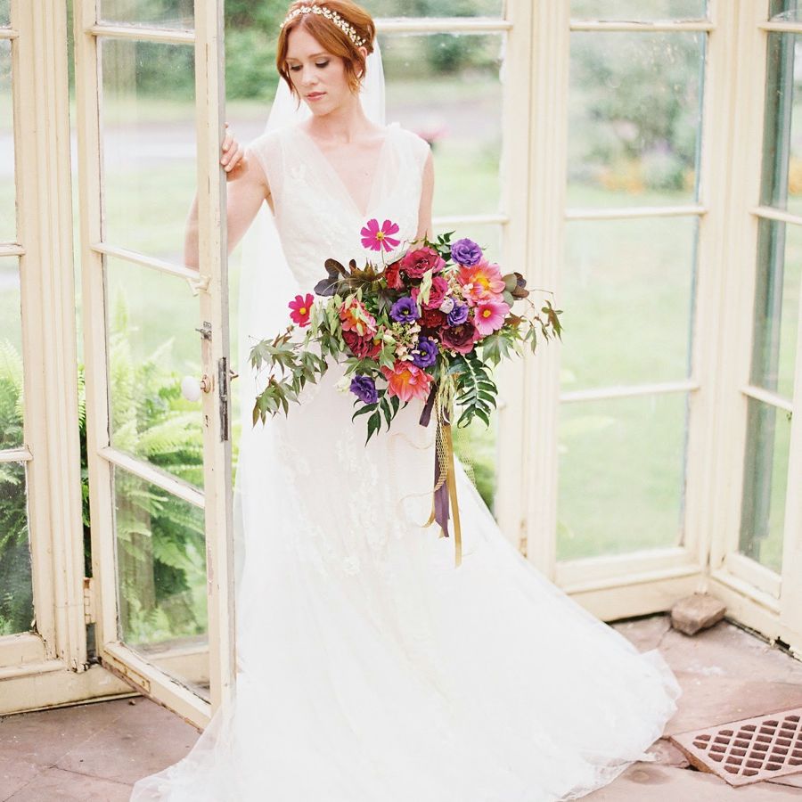 运载粉红色，紫色和绿色新月形花束的红发新娘