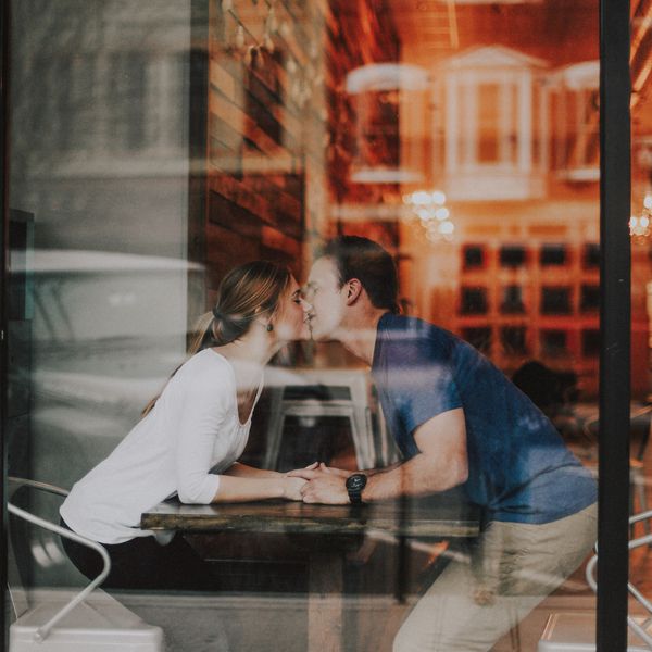 在爱的夫妇亲吻在咖啡馆的一个窗口后面