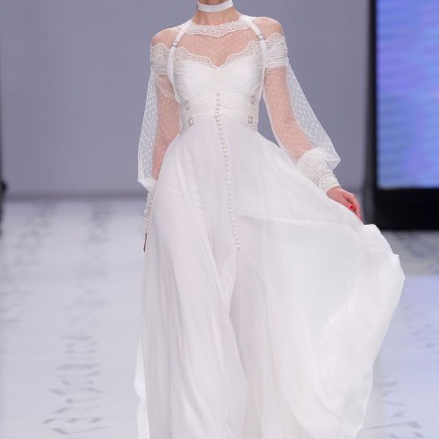 模型在流动的羽毛和班普拉连衣裙中，带有花边的领口和水钻 - 刺绣袖口，带有手工缝制的迷你窗扇和腰带