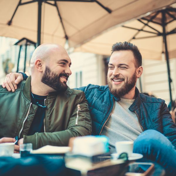 咖啡店的两个微笑的朋友“class=