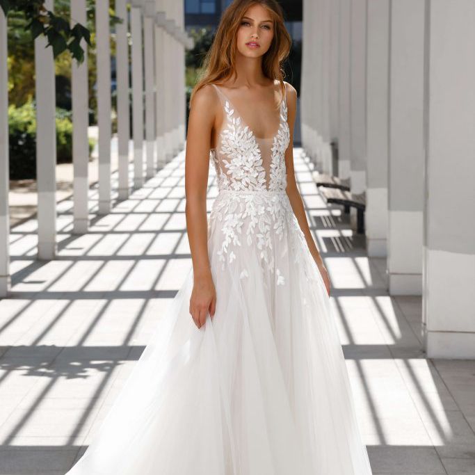 模特在低v领丝绸薄纱礼服装饰着散落的闪闪发光的叶子贴花和花卉口音。