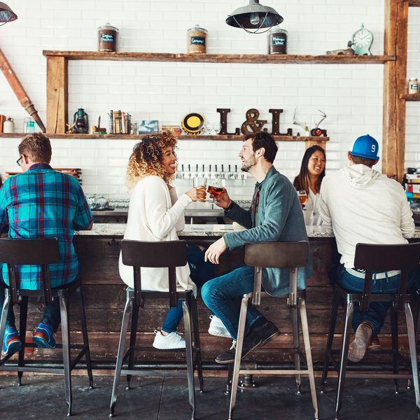 坐在一个包装的酒吧的夫妇享用饮料。