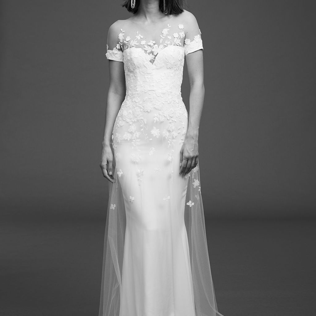 模特在短袖连衣裙与错觉领口和花的薄纱覆盖