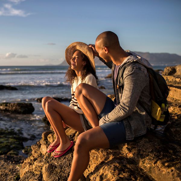 坐在海洋附近的一个岩石边缘的男人和妇女