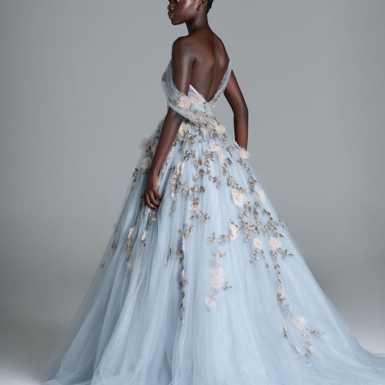 模特身穿蓝色礼服，不对称的露肩领口和3D花卉刺绣