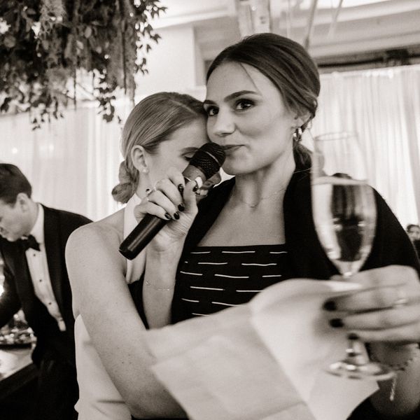 一名女子在婚礼上发表演讲，新娘拥抱她“class=