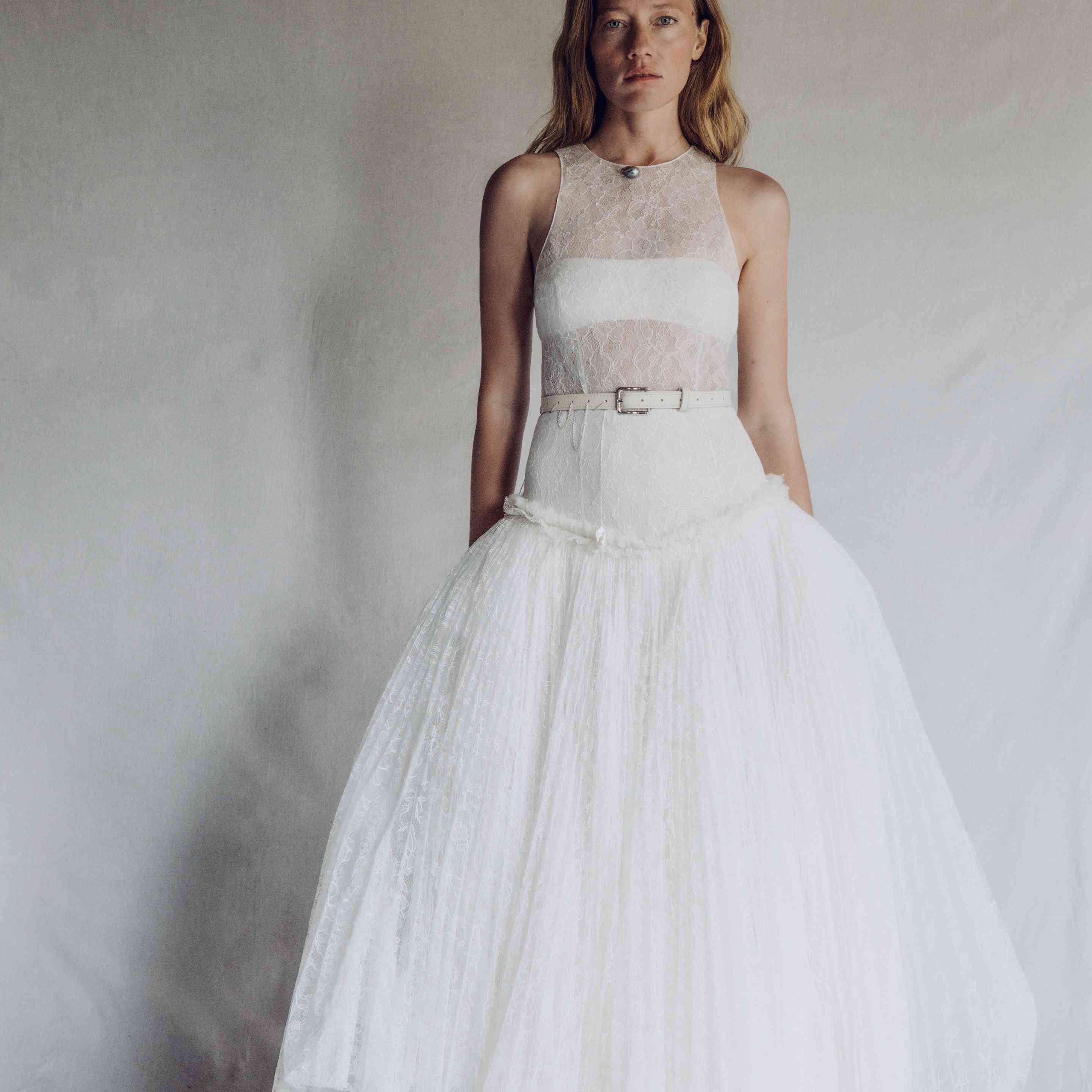 模特在尚蒂伊蕾丝垂腰礼服与百褶裙和覆盖纽扣细节搭配蕾丝胸罩和三角裤