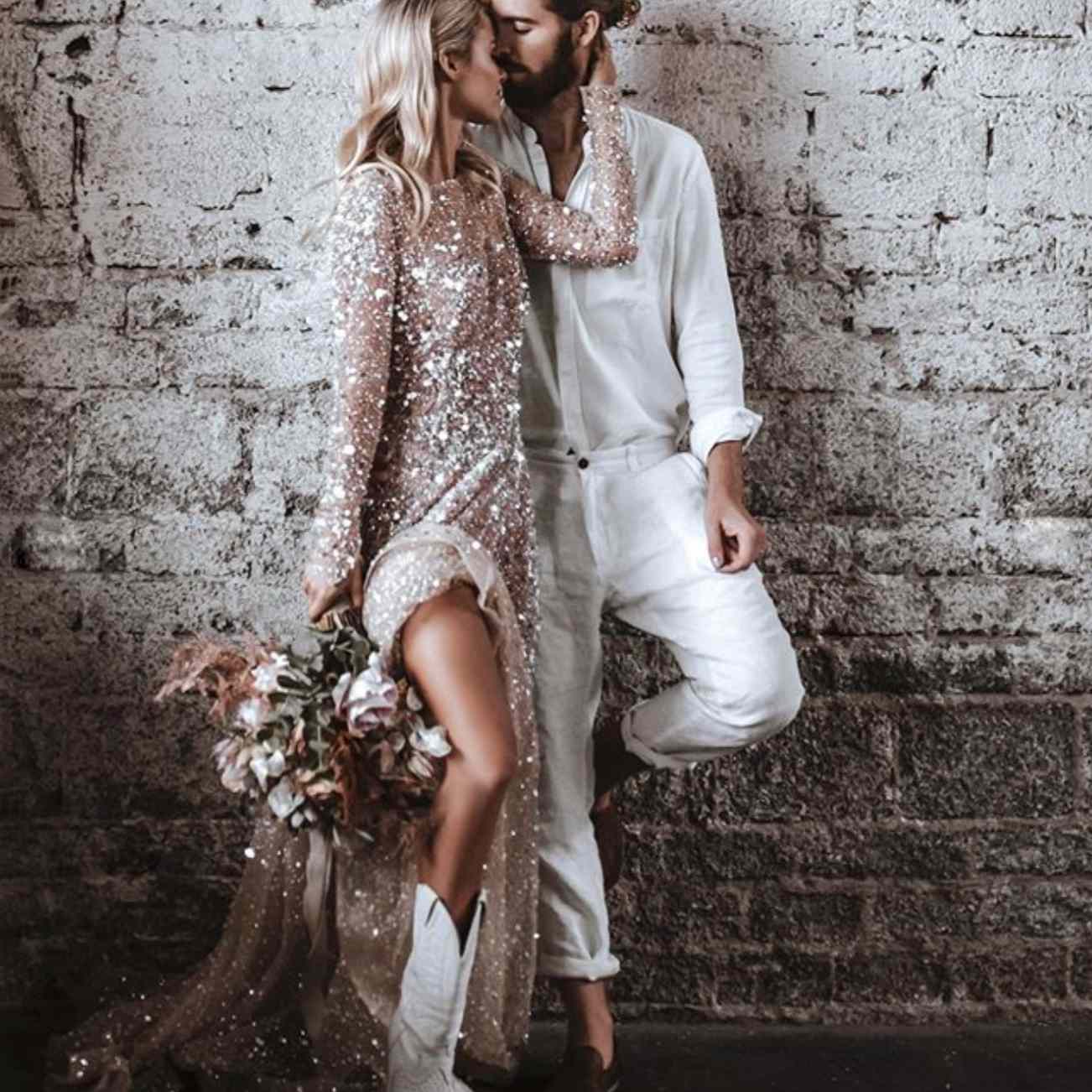 Bride and groom embracing and leaning against rock wall