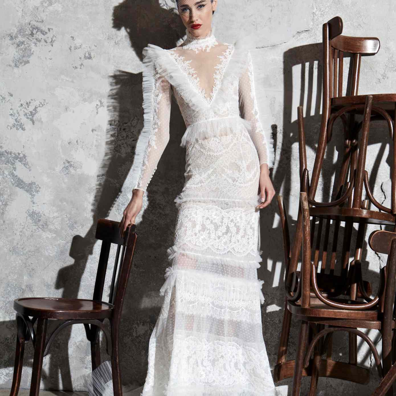 模特穿着蕾丝刺绣的高领薄纱礼服，有褶皱的薄纱领口、袖子、裙子、腰部和下摆