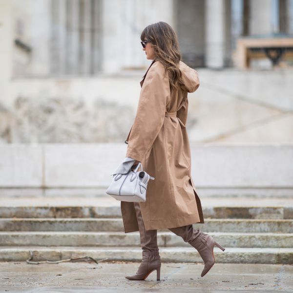 一个穿着风衣的女人走在人行道上