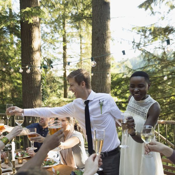 微笑的新娘和新郎在婚宴上向朋友们祝酒